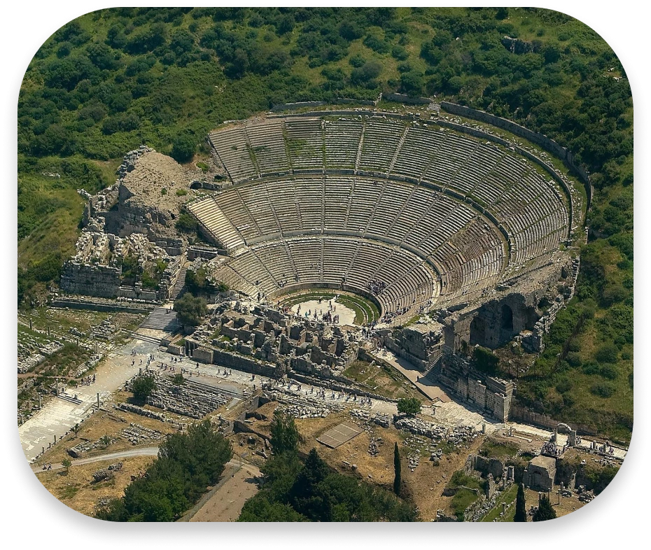 An aerial view of the Ephesus Theatre. It is shaped as a semi circle with sixty six rows of seating going up into a large hill.
